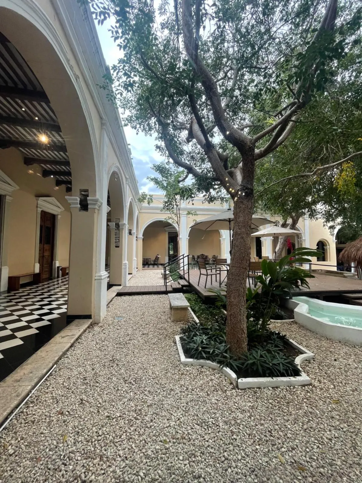 Patio colonial yucateco con arcos, gravilla y vegetación